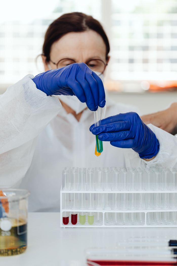 Scientist wearing gloves examining colorful liquid in test tube in lab.